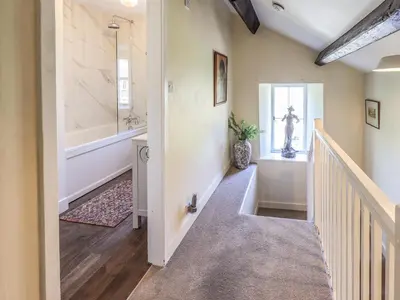 a hallway with a staircase leading to a bathroom with a tub at St Giles in Ambleside