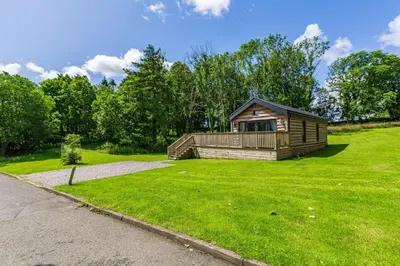 a small cabin in the middle of a grass field at Squirrel Lodge 40 with Hot Tub in Newton Stewart