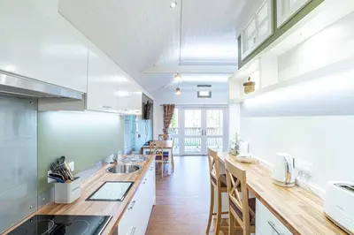 a kitchen with white cabinets and wooden counter tops at Squirrel Lodge 42 with Hot Tub in Newton Stewart