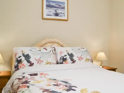 a bedroom with a bed with a floral pillow at 1 Harney Peak in Portinscale