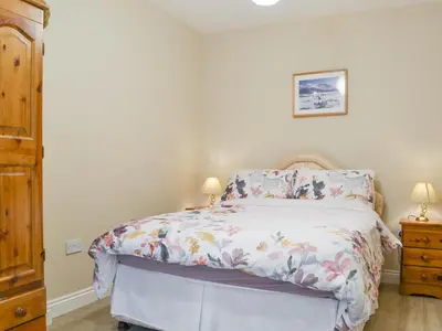 a bedroom with a bed with a floral bedspread at 1 Harney Peak in Portinscale