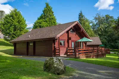 a log cabin with a rock in front of it at Lady Galloway 29 with Hot Tub in Newton Stewart