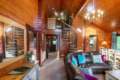 a living room with a leather couch and wooden walls at Lady Galloway 30 with Hot Tub in Newton Stewart
