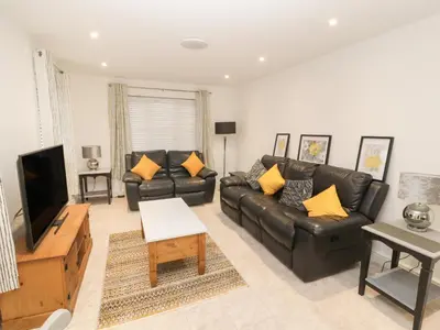 a living room with a black leather couch and a tv at Beckside House in Cockermouth