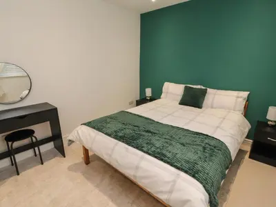 a bedroom with a bed with a green accent wall at Beckside House in Cockermouth