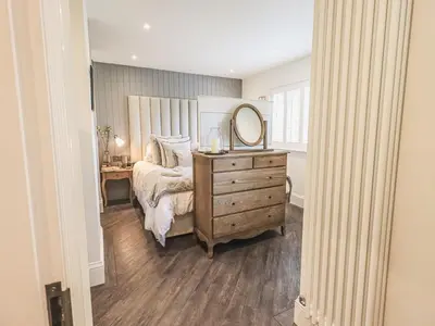 a bedroom with a bed with a mirror and a dresser at Whisk Away Cottage in Penrith