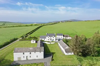 an aerial view of a large white house in a green field at High Clachan Farmhouse in Stranraer