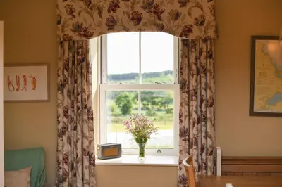 a window with a vase of flowers on a table at High Clachan Farmhouse in Stranraer