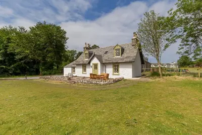 a white house with a bench in a yard at Home Farm Cottage in Stranraer