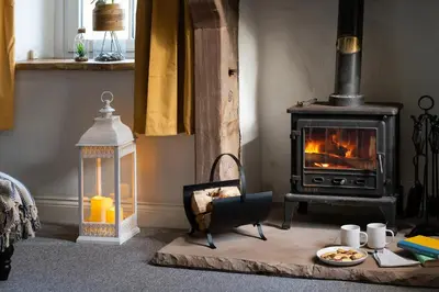 a living room with a stove and a table with food at Brow Top Cottage, Penrith, Lake District in Skelton