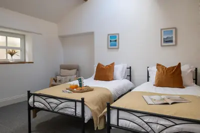 a room with two beds and a chair in it at Brow Top Cottage, Penrith, Lake District in Skelton