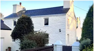 a white brick house with a black roof at Mountain Dream Cottage in Ramsey