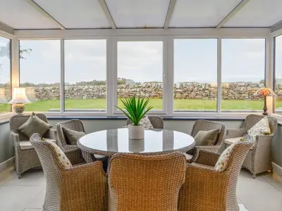 a conservatory with a table and chairs and windows at Jura in Mainsriddle