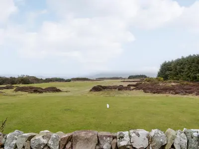 a view of a golf course with a stone wall at Jura in Mainsriddle