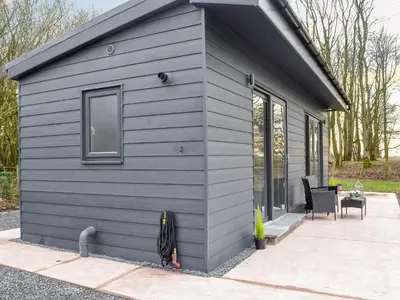 a gray tiny house with a window and a patio at Lime Tree Lodge in Castle Douglas
