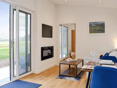 a living room with a table and blue chairs at Lime Tree Lodge in Castle Douglas