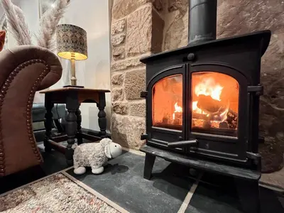 a fireplace with a teddy bear in a living room at Stylish & cosy barn minutes from the Lake District in Penrith