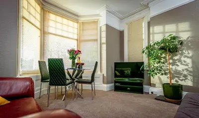 a living room with a table and chairs and a tv at Spacious Ground Floor Apartment in Keswick