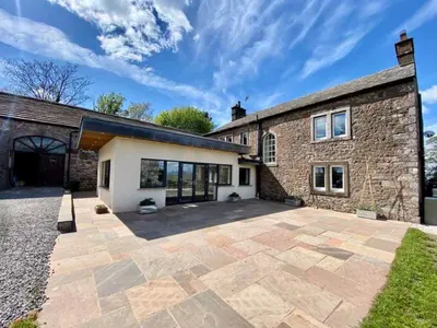 an exterior view of a brick building with a patio at Elegant & spacious farmhouse with wonderful views in Penrith