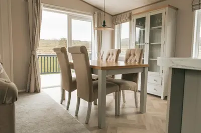 a dining room with a table and chairs and a window at Snittlegarth Farm Lodges in Wigton