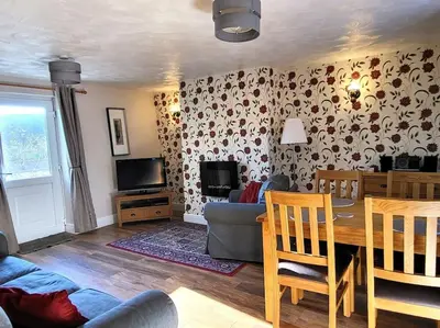 a living room with a table and a couch and a television at Pinfold Cottage on the edge of lake district in Bothel