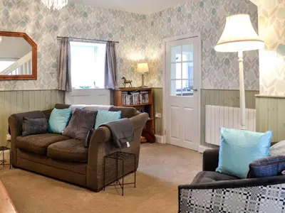 a living room with a couch and a chair at Keepers Cottage in Dumfries