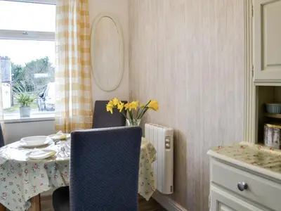 a dining room with a table and a vase of yellow flowers at Keepers Cottage in Dumfries