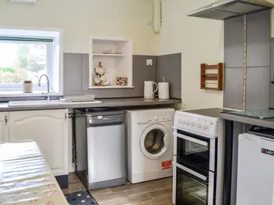 a kitchen with a washing machine and a sink at Keepers Cottage in Dumfries