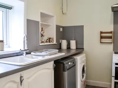 a kitchen with a sink and a washing machine at Keepers Cottage in Dumfries