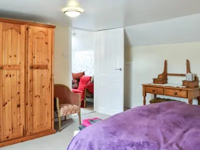 a bedroom with a purple bed and a wooden closet at Keepers Cottage in Dumfries