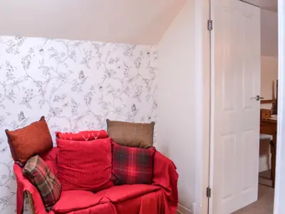 a red couch with pillows in a living room at Keepers Cottage in Dumfries