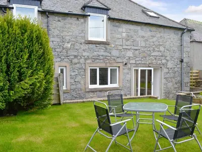 a table and chairs in front of a stone house at Kirroughtree Steading 2 - Uk42904 in Newton Stewart