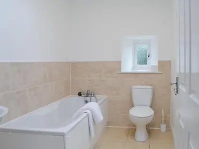 a white bathroom with a tub and a toilet at Kirroughtree Steading 2 - Uk42904 in Newton Stewart