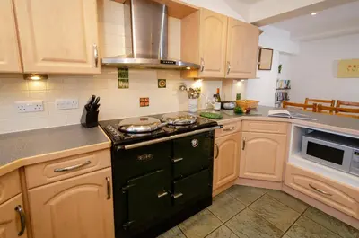 a kitchen with wooden cabinets and a stove top oven at Bens Cottage in Chapel Stile