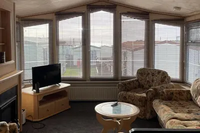 a living room with a couch and a tv and some windows at Immaculate 2-Bed Static Caravan at Monrieth in Newton Stewart