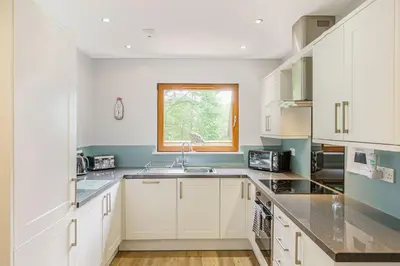 a kitchen with white cabinets and a window at Lord Galloway 32 with Hot Tub in Newton Stewart