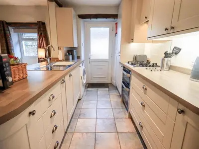 a kitchen with white cabinets and a tile floor at The Old Betting Shop in Keswick