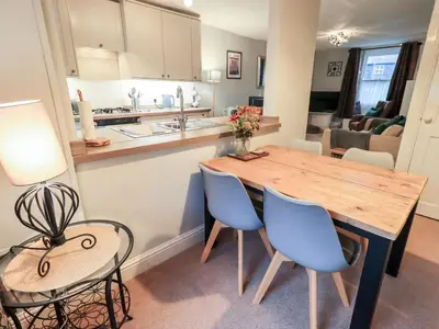 a kitchen and living room with a wooden table and chairs at The Old Betting Shop in Keswick