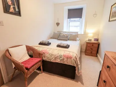 a bedroom with a bed with a chair and a window at The Old Betting Shop in Keswick