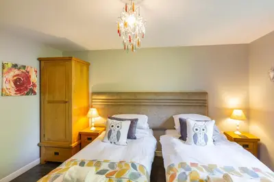 a bedroom with two beds and a chandelier at Lord Galloway 34 with Hot Tub in Newton Stewart