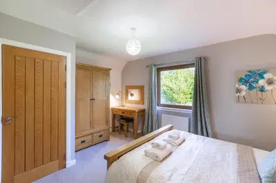 a bedroom with a bed and a desk and a window at Lord Galloway 34 with Hot Tub in Newton Stewart