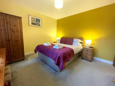 a bedroom with a large bed and a night stand at Beautiful Rural 3BR Cottage with Stunning Views - Pass the Keys in Auldgirth