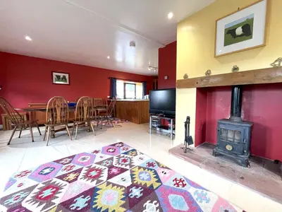a living room with a table and a wood stove at Beautiful Rural 3BR Cottage with Stunning Views - Pass the Keys in Auldgirth