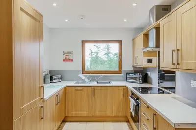 a kitchen with wooden cabinets and a window at Lord Galloway 35 with Hot Tub in Newton Stewart