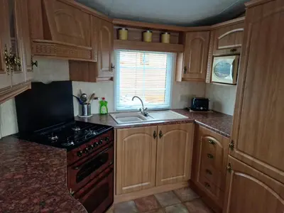 a kitchen with wooden cabinets and a sink and a stove at Stunning Caravan Whithorn3 in Newton Stewart