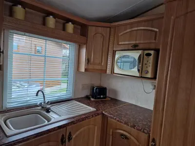 a kitchen with a sink and a microwave at Stunning Caravan Whithorn3 in Newton Stewart