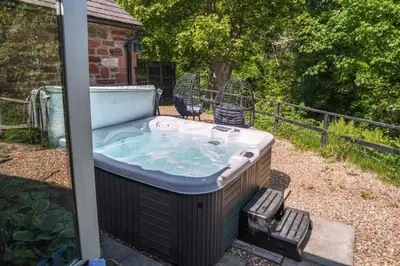 a hot tub in a yard with two chairs at Beckside Cottage, near Carlisle romantic cottage with hot tub in Longtown