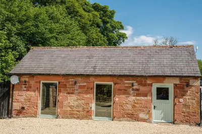 an old red brick building with a gray roof at Beckside Cottage, near Carlisle romantic cottage with hot tub in Longtown
