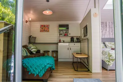 a tiny house with a kitchen and a living room at Reflections, Netherby, a micro cabin with hot tub in a rural setting in Longtown