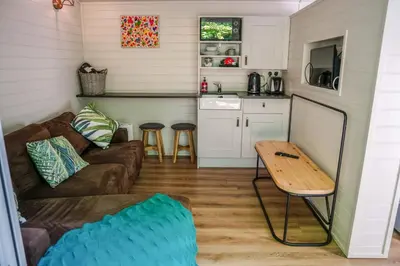 a living room with a couch and a table at Reflections, Netherby, a micro cabin with hot tub in a rural setting in Longtown